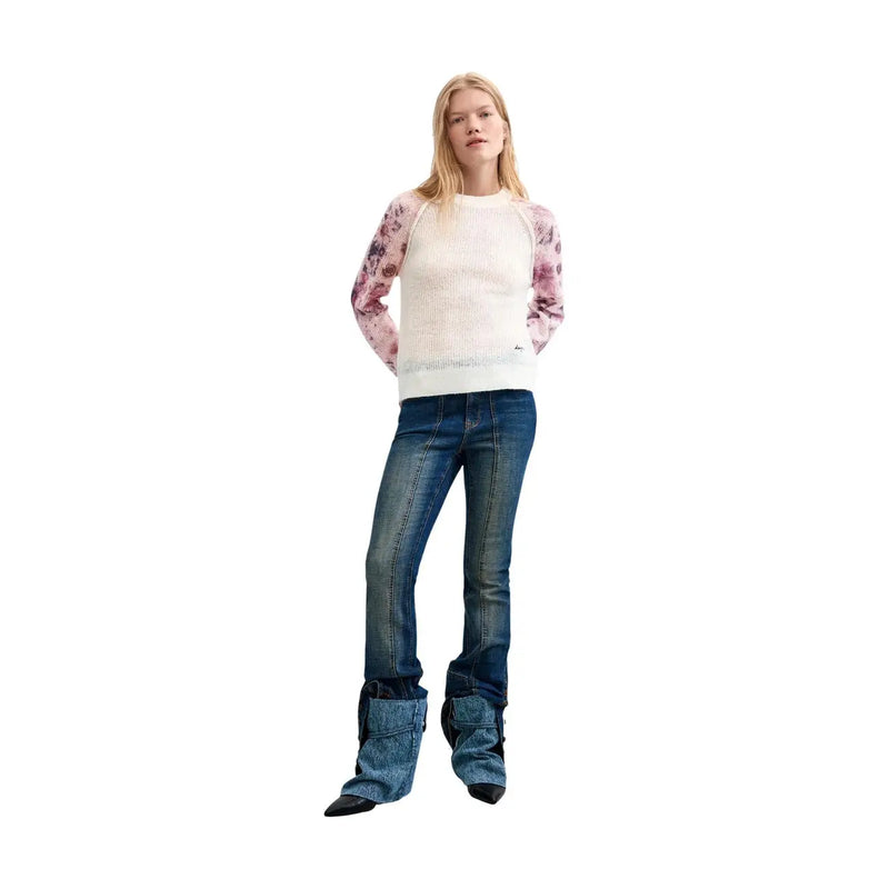 A woman wearing a Desigual women floral knit sweater white wool blend with pink floral sleeves and dark blue flared jeans