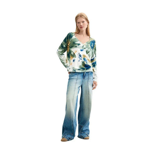 Eine Frau trägt eine weiße Viskosebluse von Desigual mit langen Ärmeln und einem abstrakten Blumenmuster.