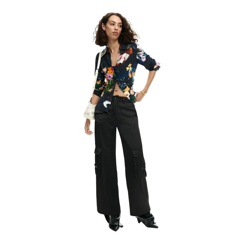A woman wears a desigual women long floral viscose v neck shirt in dark blue with vibrant blossoms over black cargo pants