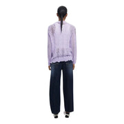 Woman from behind wearing light purple long-sleeved top and dark blue wide-leg jeans