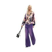 A woman wearing a desigual women pink floral cotton knit sweater paired with wide-leg purple trousers