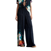 Black wide-leg viscose trousers by Desigual featuring a vibrant tropical floral print down the side
