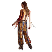 A woman wears desigual women trousers mustard viscose with belt paired with a vibrant patterned jumpsuit