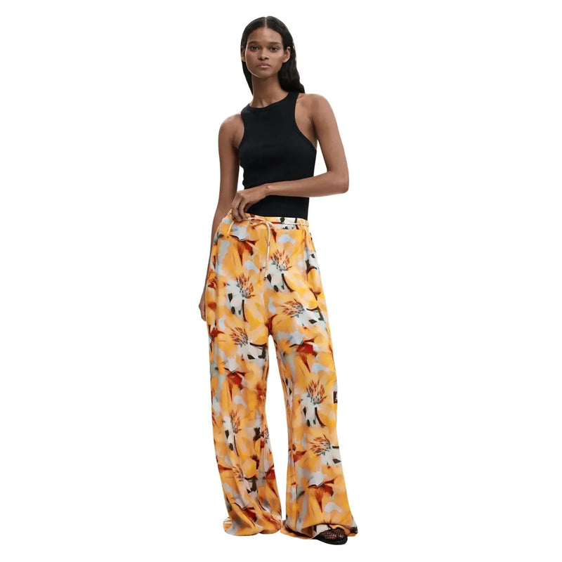 Wide-leg trousers in vibrant yellow floral print with orange and white accents made from lightweight viscose fabric by Desigual