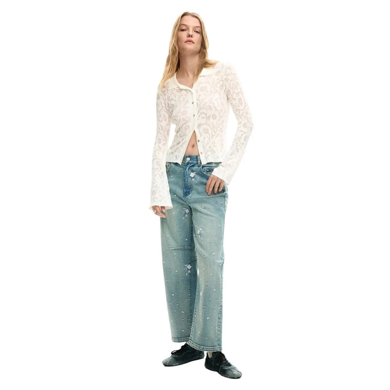 A woman wears a desigual white viscose long-sleeved lace button-up shirt with light-wash floral embroidered jeans