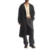 Schwarzer, doppelreihiger Trenchcoat mit klassischem Kragen und geknöpften Manschetten, kombiniert mit braunen Dr. Martens Herren-Ankle-Boots aus Leder (Ambassador).