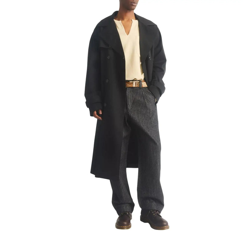 Schwarzer, doppelreihiger Trenchcoat mit klassischem Kragen und geknöpften Manschetten, kombiniert mit braunen Dr. Martens Herren-Ankle-Boots aus Leder (Ambassador).