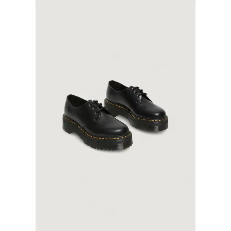 Chaussures Dr. Martens pour femmes, en cuir noir à lacets, vues de l'arrière, avec semelle extérieure et coutures emblématiques.