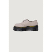 A beige leather slip-on Dr Martens shoe for women shown from the back side highlighting its material and design