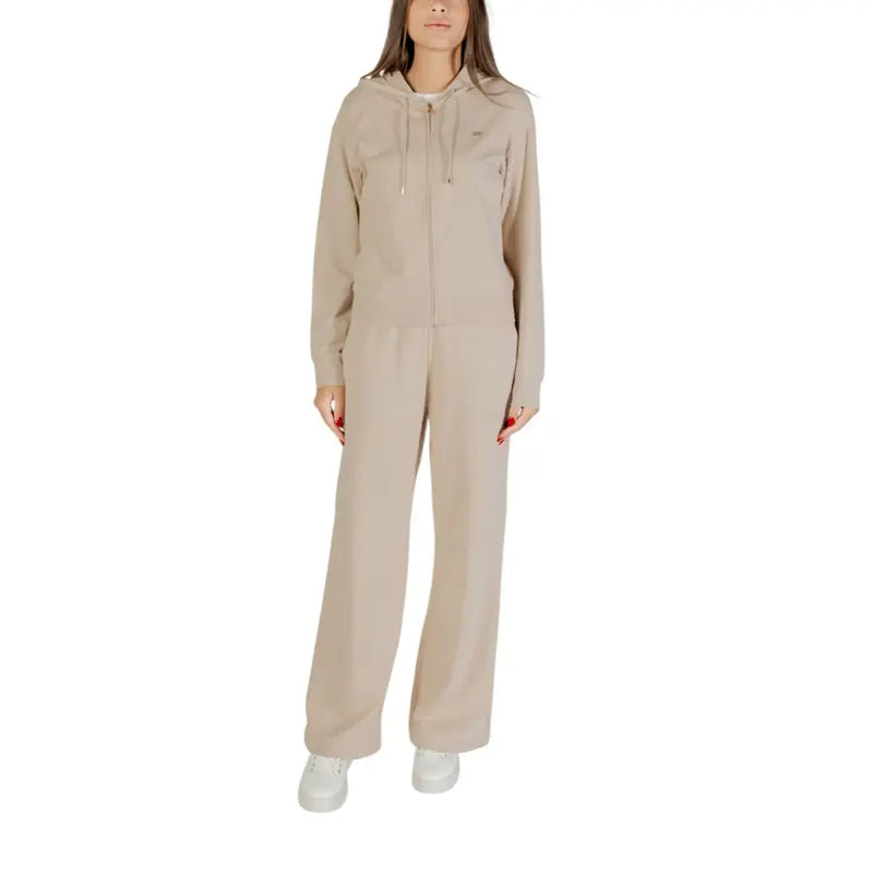 Woman wearing a beige hooded cotton elastane jumpsuit with front pockets and zipper