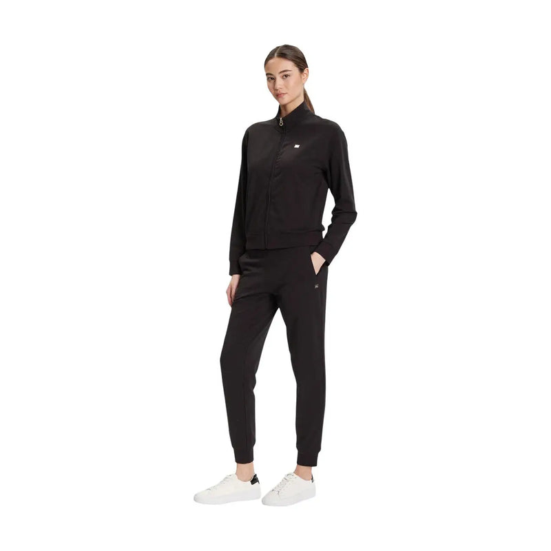 Ea7 Schwarzer Damen-Overall aus Baumwolle mit Rollkragen, kombiniert mit schwarzem Tommy Hilfiger Trainingsanzug mit Reißverschluss und weißen Sneakers.