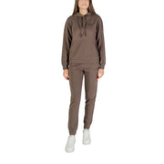 Women wearing a brown hooded tracksuit with white sneakers in EA7 printed black jumpsuit display