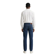 Dark blue denim jeans with classic five-pocket design and subtle faded wash paired with gant men shirt