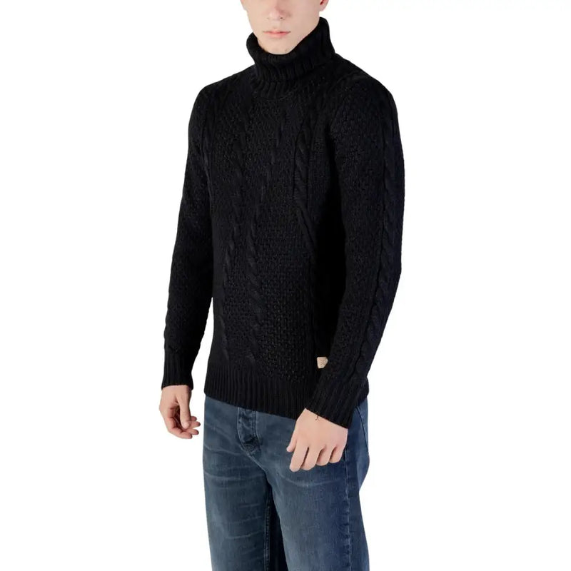 Black cable knit turtleneck sweater with a ribbed texture and brand label on the left side.