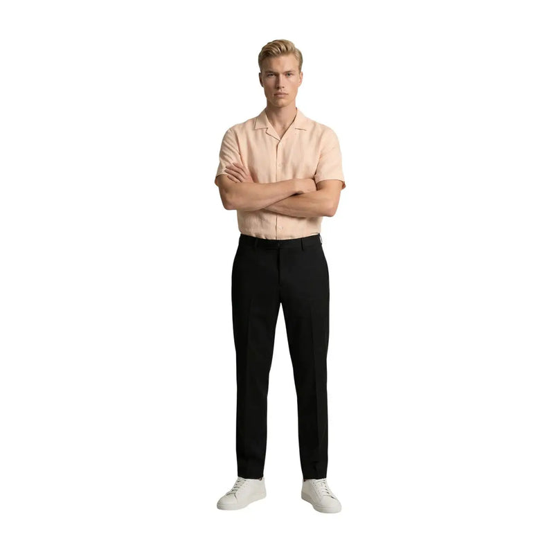 A man wearing gianni lupo men black polyester viscose trousers paired with a light peach short-sleeved shirt and white sneakers