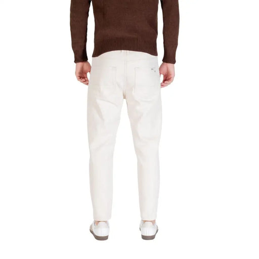 Cream-colored slim-fit denim trousers in white cotton with a clean back pocket design shown from the back by Gianni Lupo