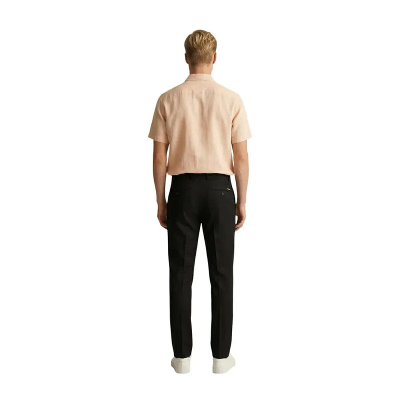 A man wearing a light peach short-sleeved Gianni Lupo men shirt paired with black tailored trousers