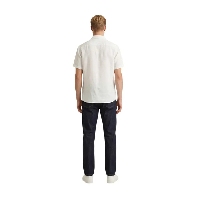 A man wearing a Gianni Lupo men shirt in white short-sleeved cotton with dark blue denim jeans