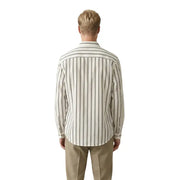 A man wearing a cream-colored long-sleeved Gianni Lupo men shirt with thin vertical charcoal gray stripes