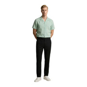 A man wearing a light green short-sleeved Gianni Lupo men shirt paired with black trousers and white sneakers