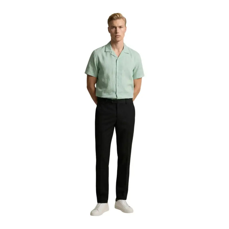A man wearing a light green short-sleeved Gianni Lupo men shirt paired with black trousers and white sneakers