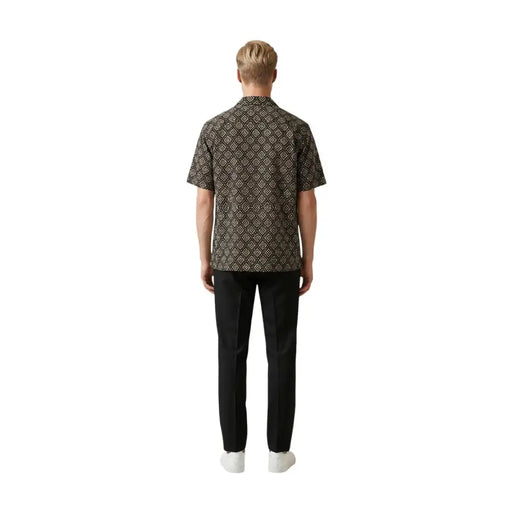 A man wearing a gianni lupo men shirt in dark brown with an intricate gold geometric pattern and short sleeves