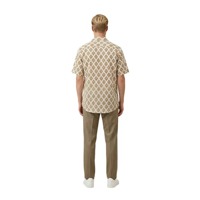 A man wearing a beige Gianni Lupo men shirt with a repeating brown and cream geometric pattern and short sleeves
