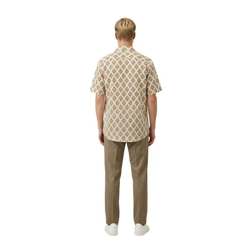 A man wearing a beige Gianni Lupo men shirt with a repeating brown and cream geometric pattern and short sleeves