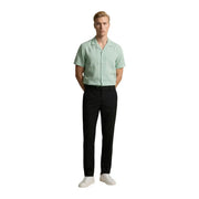 A man wearing a light green short-sleeved Gianni Lupo men shirt paired with black trousers and white sneakers