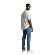 A man wearing a gianni lupo white round neck t shirt made of 100% cotton paired with medium-wash blue jeans