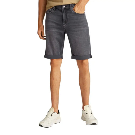 Man wearing gray denim shorts and tan T-shirt, suitable for casual summer wear