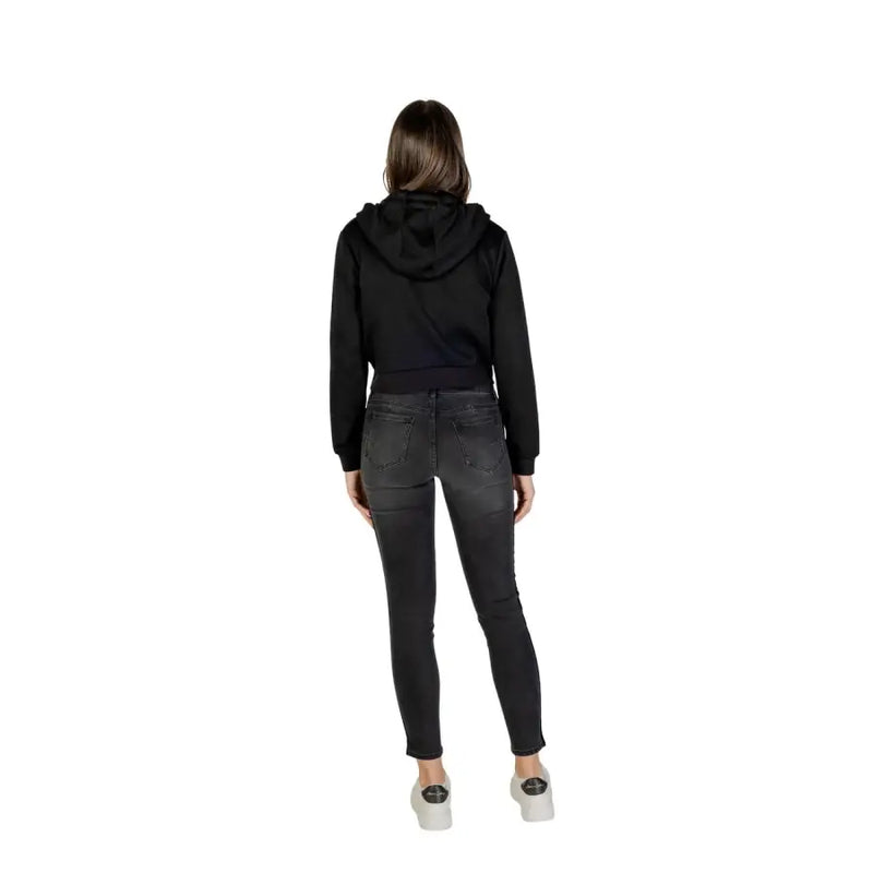 Guess Active women black full zip hooded sweatshirt with hood and long sleeves paired with dark gray skinny jeans