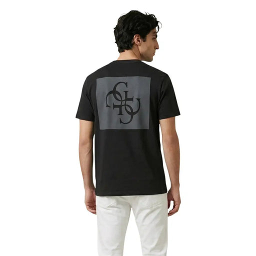 Back of black Guess men t-shirt with gray rectangular patch featuring intricate black monogram design