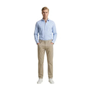 A man wearing beige Guess slim fit cotton blend trousers paired with a light blue button-down shirt