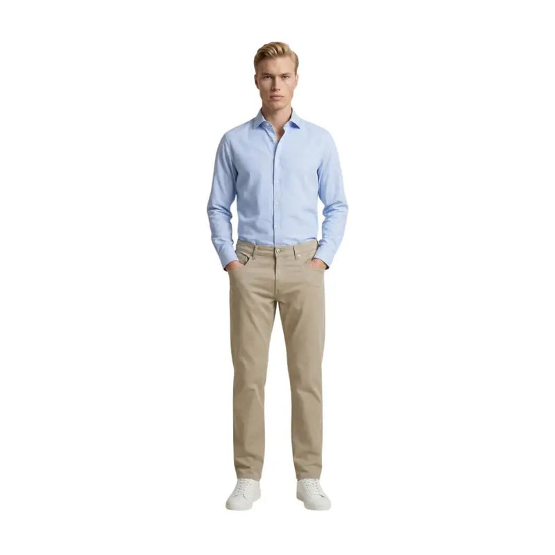 A man wearing beige Guess slim fit cotton blend trousers paired with a light blue button-down shirt