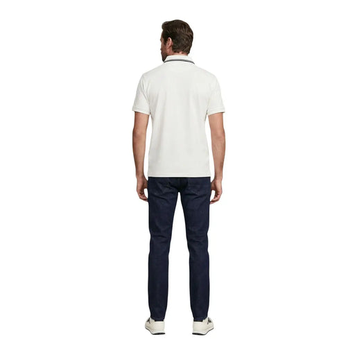 A man wearing a Guess men white short sleeve cotton blend polo shirt with navy trim and dark denim jeans