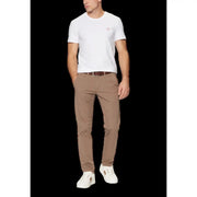 A pair of beige slim fit chino trousers with subtle creasing worn by a model with a guess men’s white round neck t shirt