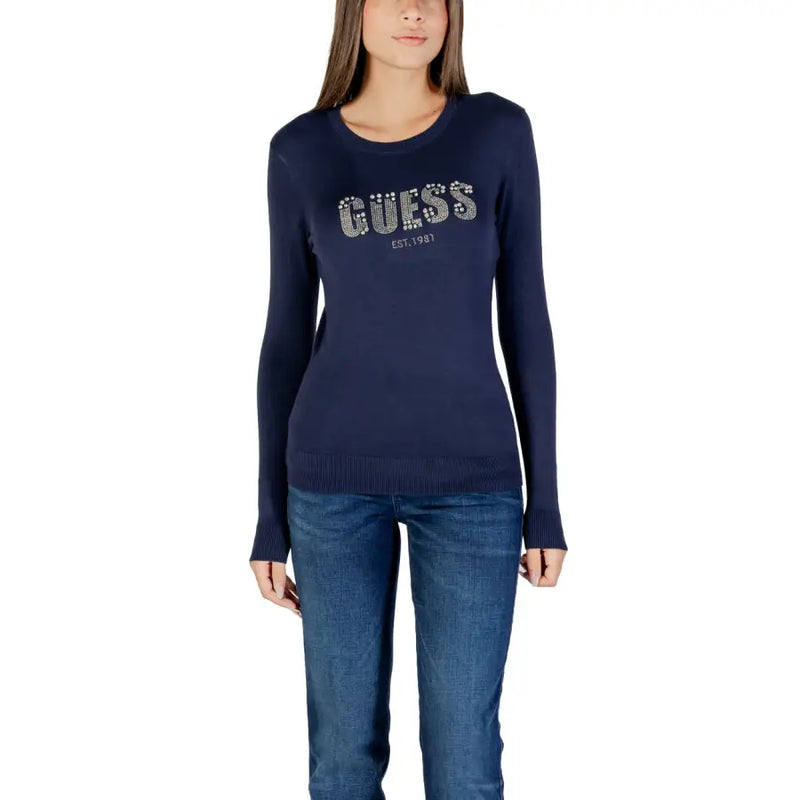 Woman wearing navy blue long-sleeved T-shirt with sparkly GUESS EST 1981 graphic