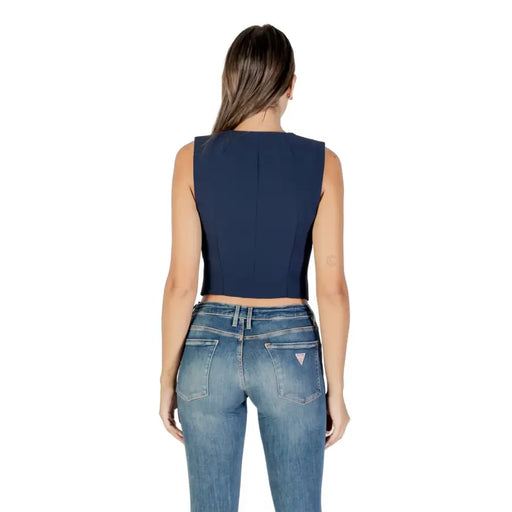 Woman wearing navy blue sleeveless cropped top and blue denim jeans for Guess Women Gilet