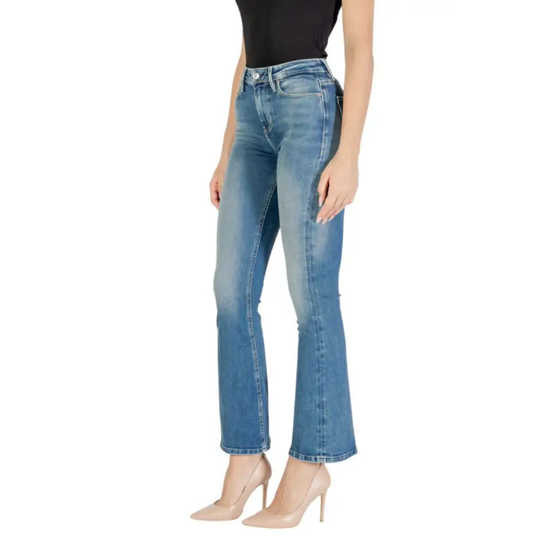 Woman wearing black tank top and blue flared jeans with nude heels showcasing Guess Light Blue Fall Winter Zip Button Jeans