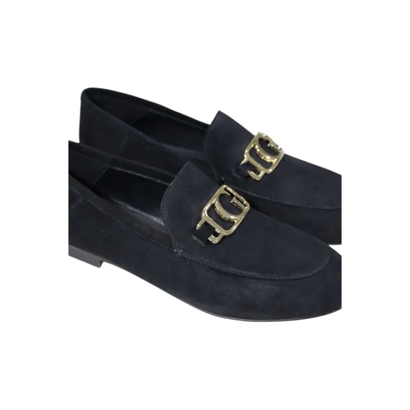 Guess women’s black leather moccasin flats featuring black suede loafers with gold-tone metallic buckles
