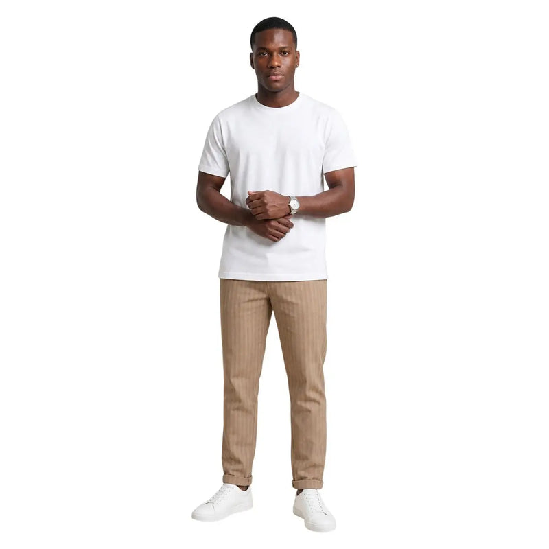 A man wearing hydra men beige striped cotton trousers paired with a white short-sleeved crew neck t-shirt and white sneakers