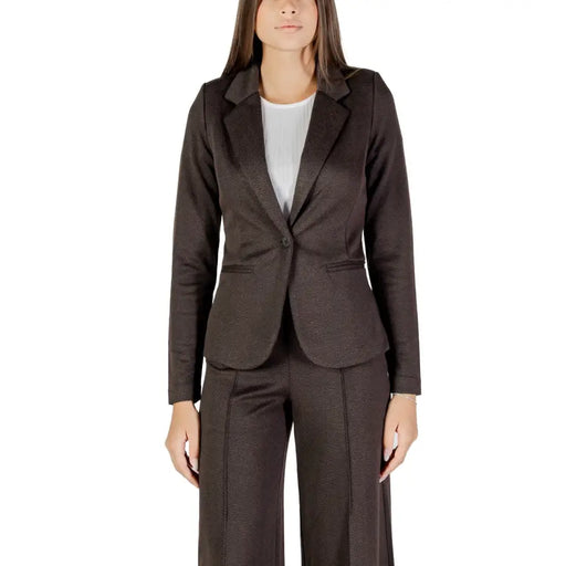 Woman wearing a dark brown single-breasted pantsuit with a white top from Ichi Women Fall Winter collection