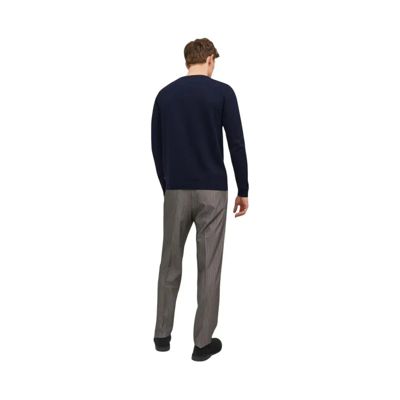 A man wearing jack & jones blue v-neck knitwear in navy blue long-sleeved knit sweater with gray pinstripe trousers