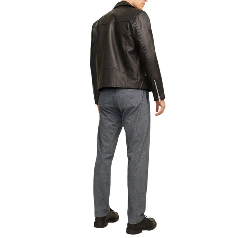 Black leather biker jacket with sleeve and back zippers shown from the back paired with jack and jones grey cotton stretch trousers for men fall winter