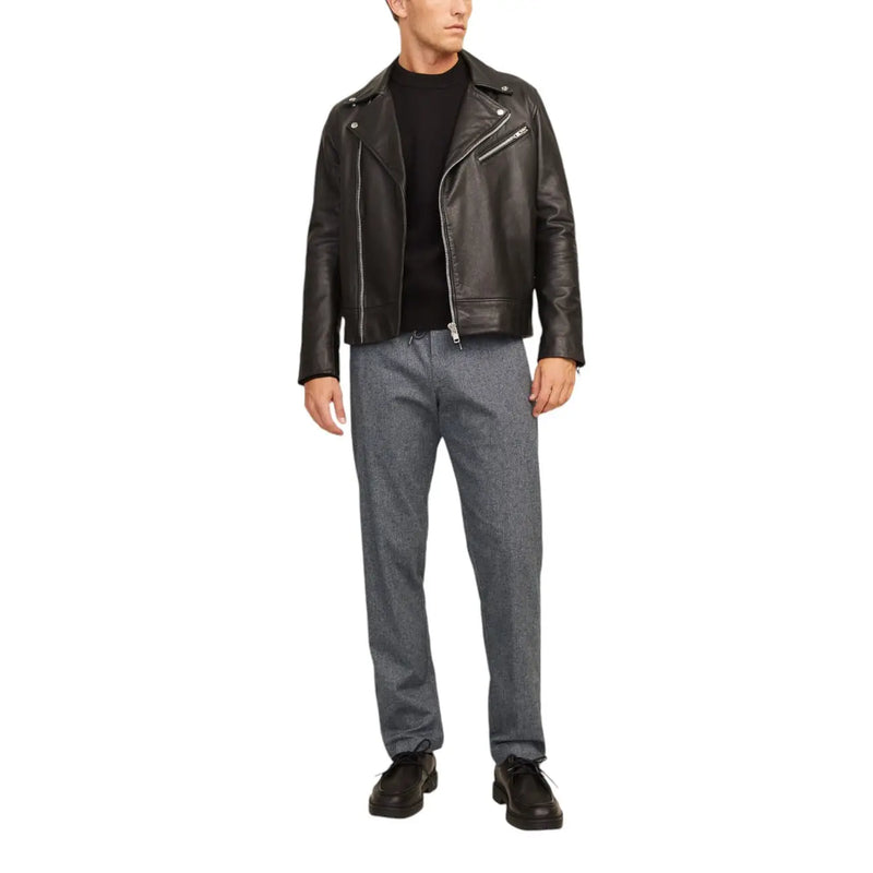 Black leather biker jacket with silver zippers and snap buttons paired with jack & jones grey cotton stretch trousers for men fall winter