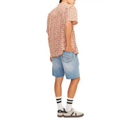 A person wearing Jack & Jones light blue cotton shorts paired with a short-sleeved skull pattern button-up shirt