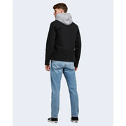 Schwarze Kapuzenjacke mit grau gefütterter Kapuze, von hinten gesehen, kombiniert mit blauen Jack & Jones Herrenjeans aus 100 % Baumwolle.
