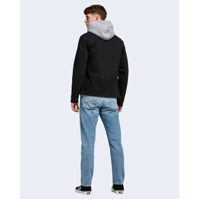 Schwarze Kapuzenjacke mit grau gefütterter Kapuze, von hinten gesehen, kombiniert mit blauen Jack & Jones Herrenjeans aus 100 % Baumwolle.