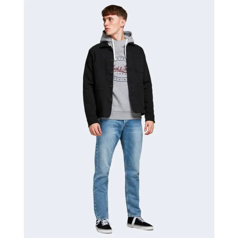 Schwarze, geknöpfte Jacke mit Kapuze und Vordertaschen, kombiniert mit blauen Herrenjeans von Jack & Jones aus 100 % Baumwolle.